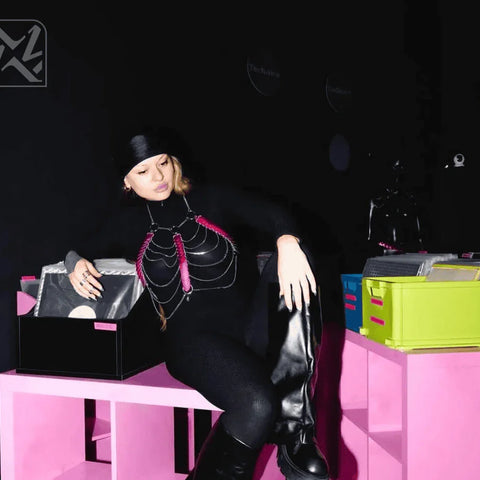 Frau trägt schwarze Bodychain-Harness mit silbernen Ketten und pinken Akzenten, moderner, cooler Style, selbstbewusstes Auftreten.