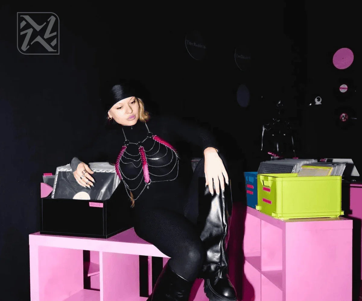 Frau trägt schwarze Bodychain-Harness mit silbernen Ketten und pinken Akzenten, moderner, cooler Style, selbstbewusstes Auftreten.