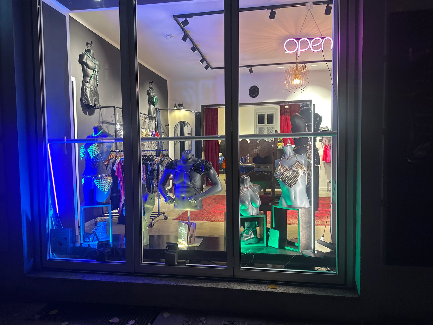 Schaufenster mit silbernen Scalemail-Bodychains und Harnesses auf Mannequins, futuristisch, glamourös, leuchtende Farben, elegante Atmosphäre