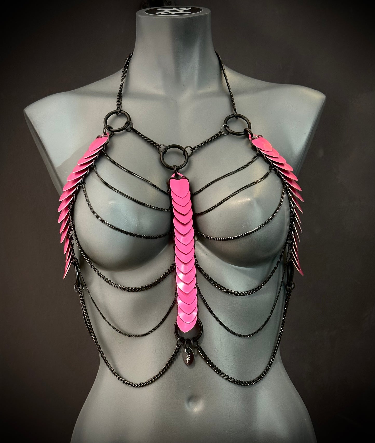 Bodychain Schmuck in Schwarz mit pinken Schuppen-Elementen, moderner Stil, auffällig und kraftvoll