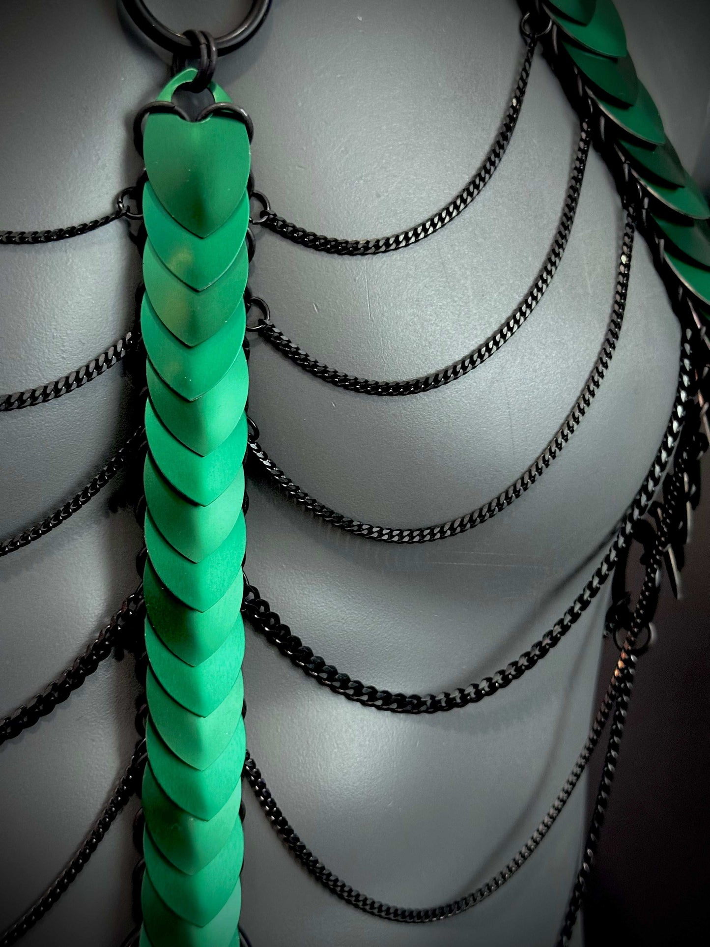 Aphrodite Fire Harness aus schwarzen Ketten und grünen Schuppen, futuristisch und kraftvoll