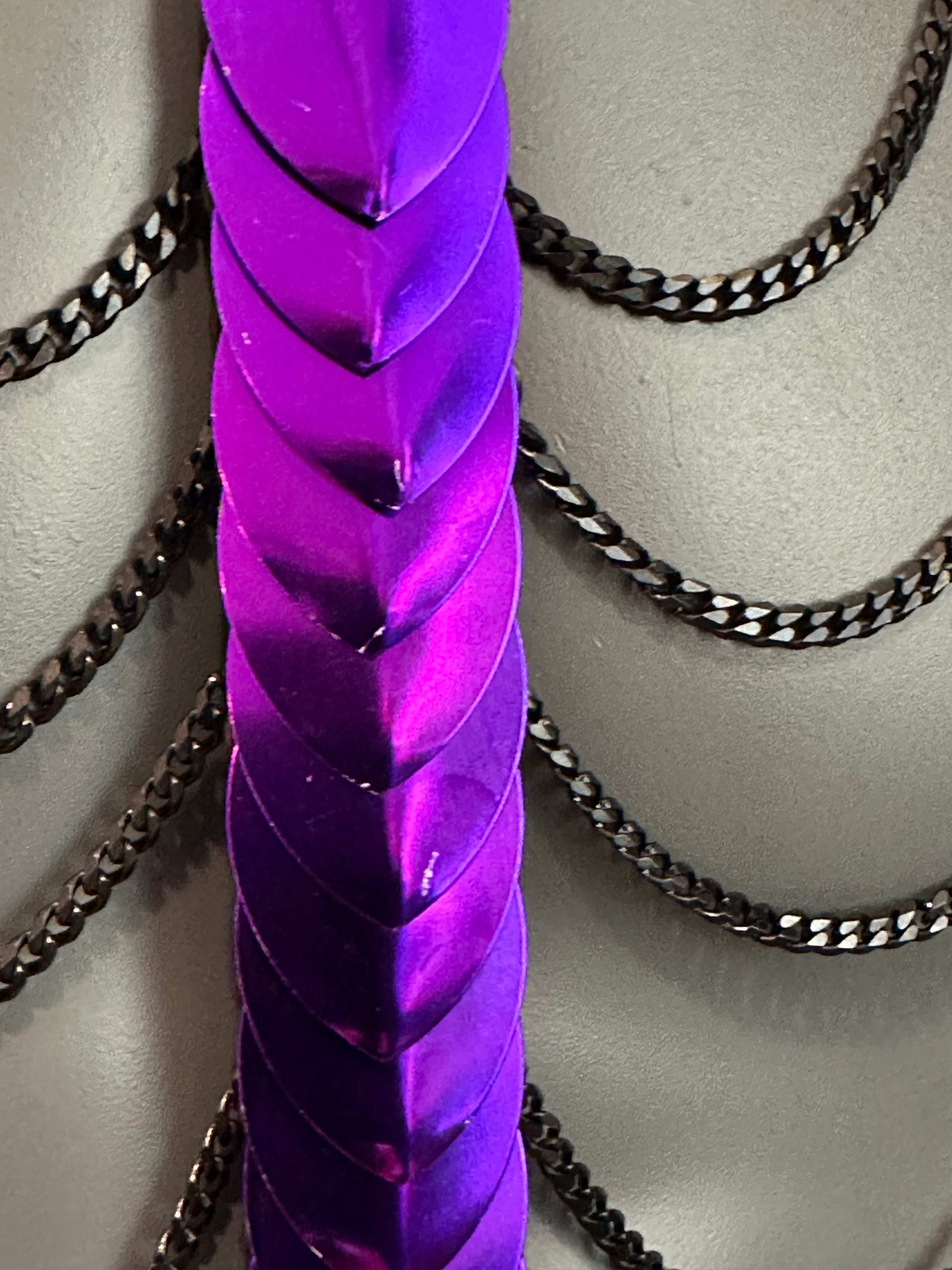 Metallkunstwerk in glanzendem violett mit schwarzen Ketten, modern und kraftvoll