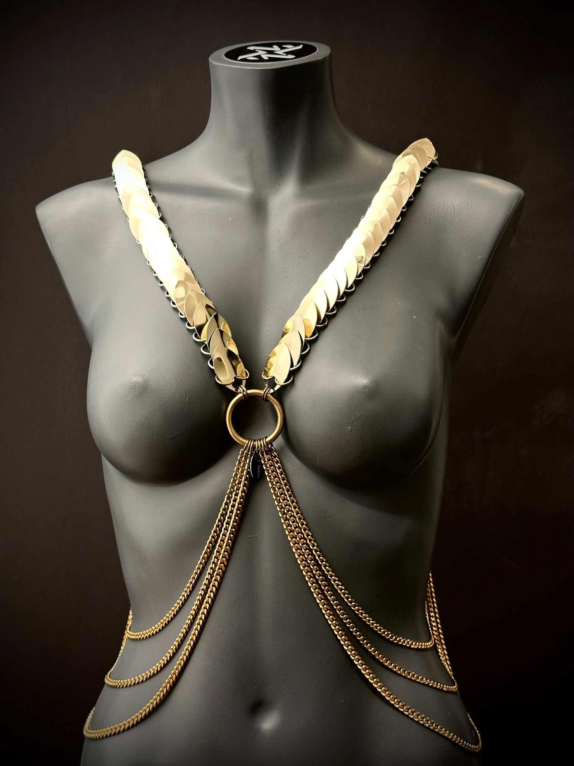 Lisa Majun Ariv Harness goldfarben glänzend, stilvoll und selbstbewusst am schwarzen Schaufenster