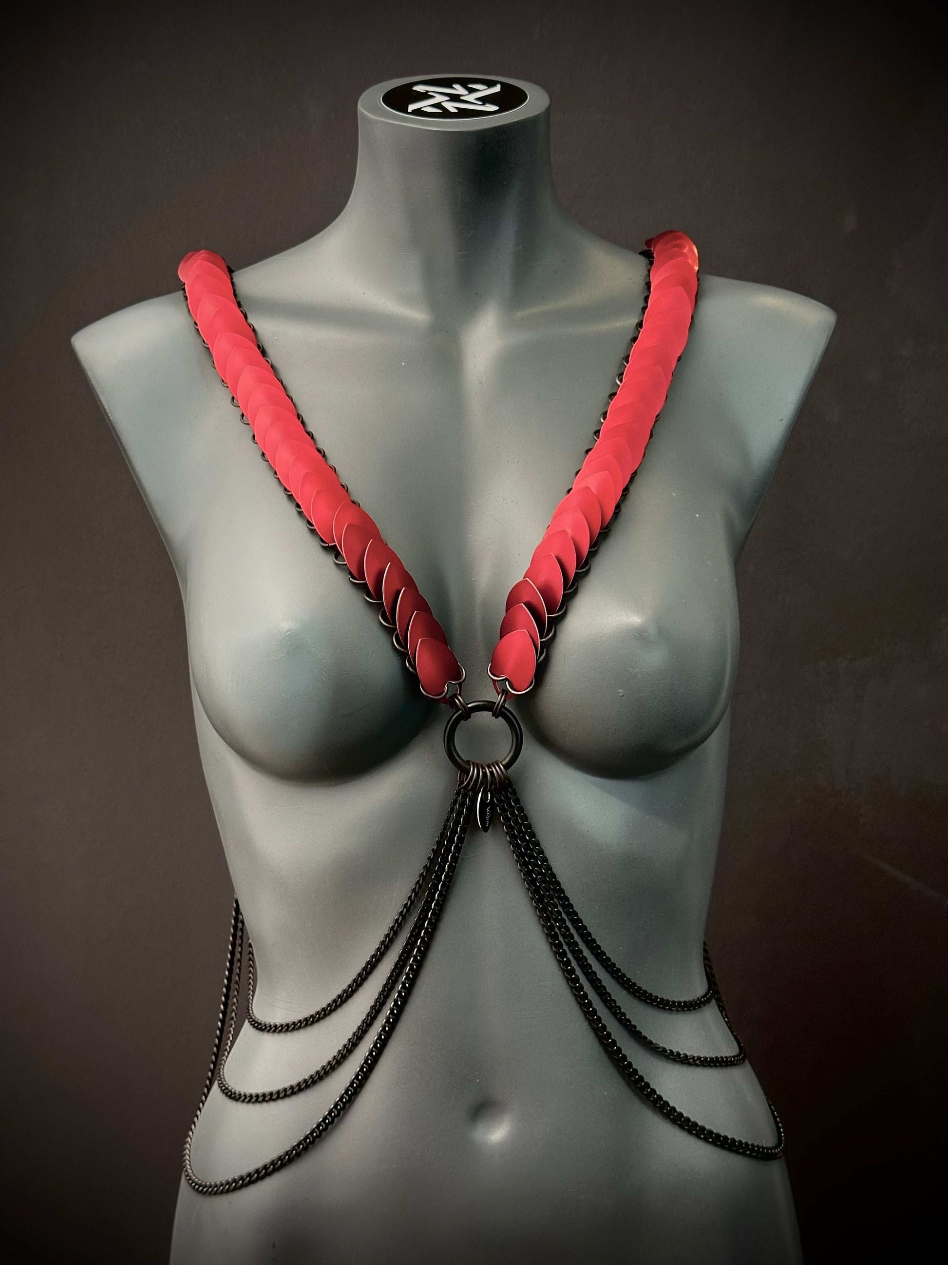 Armband Harness in Schwarz und Rot aus Ketten am grauen Schaufenster, kraftvoll und provokativ