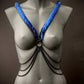 Ariv Harness blau mit Metallketten, modisch und kraftvoll, ausdrucksstark am grauen Schaufenster