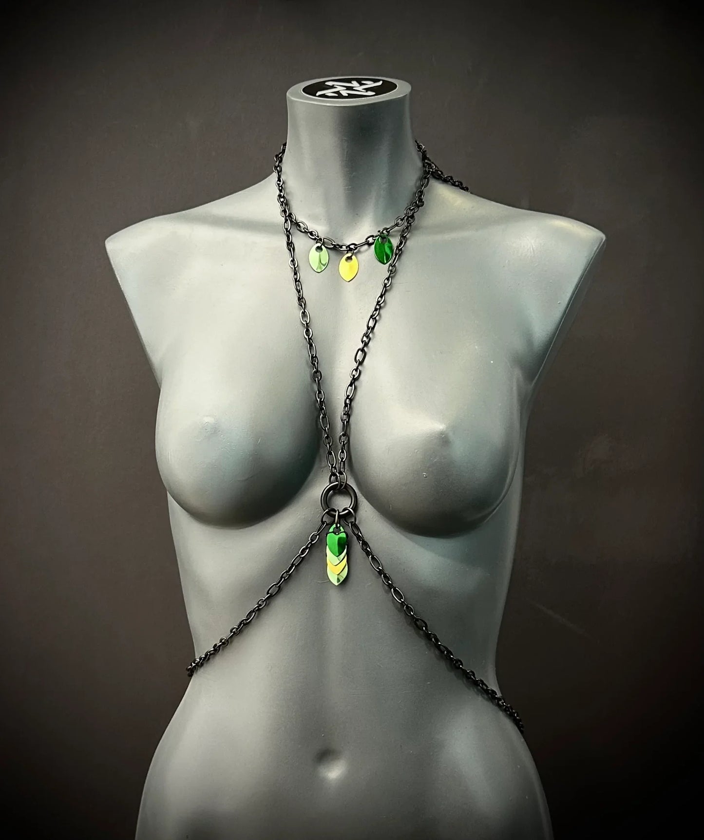 Freyja Bodychain in Schwarz mit grünen und gelben Akzenten an grauem Schaufenster für modernen Look