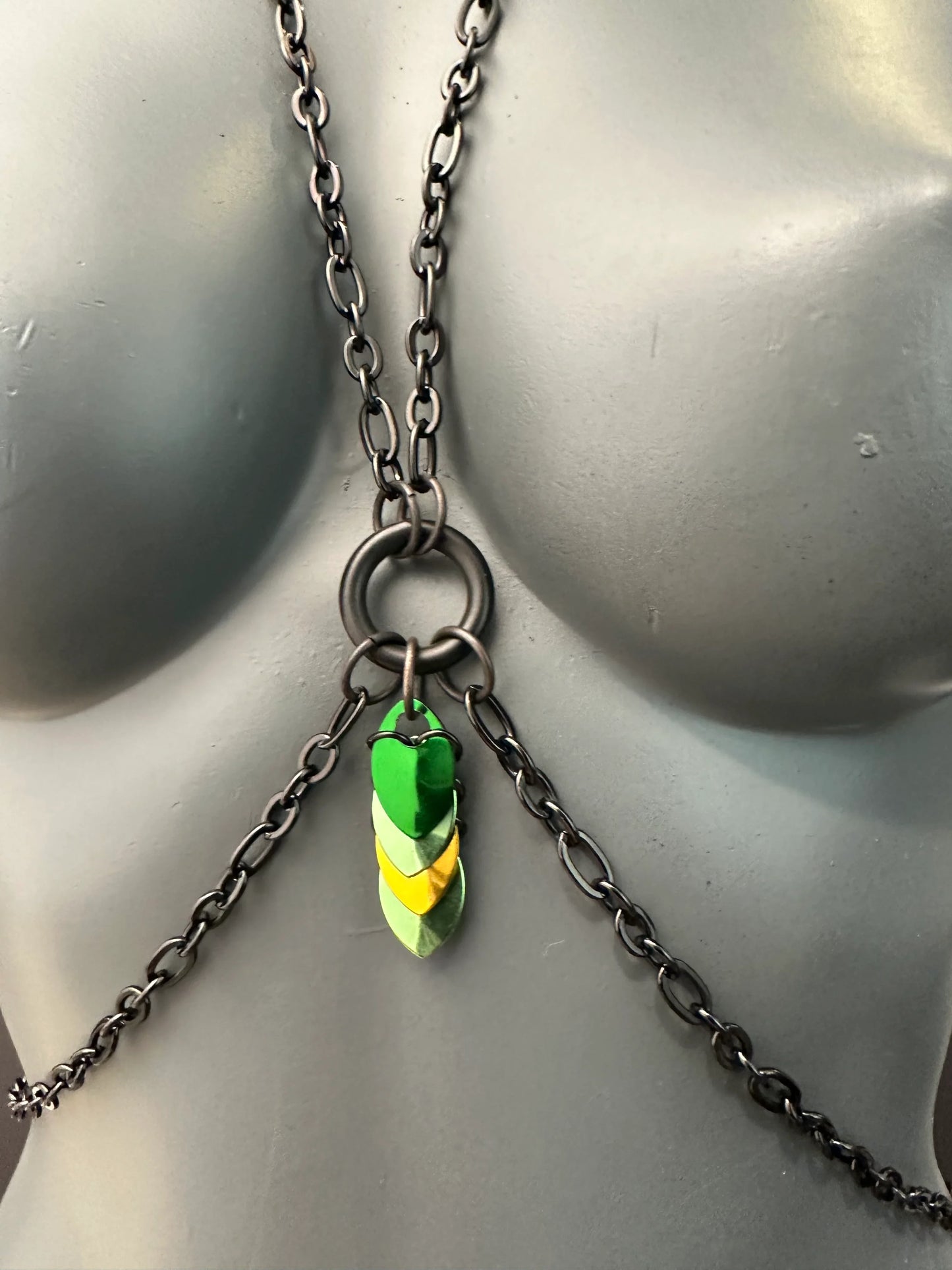 Bodychain aus schwarzer Metallkette mit grün-gelben Anhängern, moderner und selbstbewusster Stil