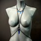 schwarze Bodychain mit blauen Anhängern am grauen Frauenfigur-Mannequin, moderner Stil, elegant
