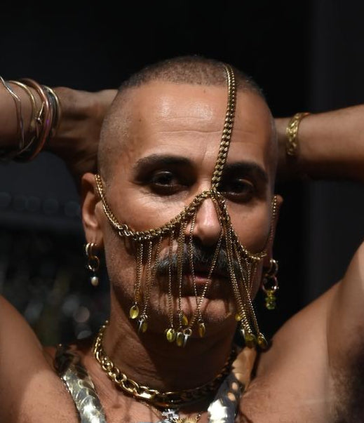 Goldfarbene Facechain aus Ketten mit Anhängern, künstlerisch und ausdrucksstark am männlichen Model