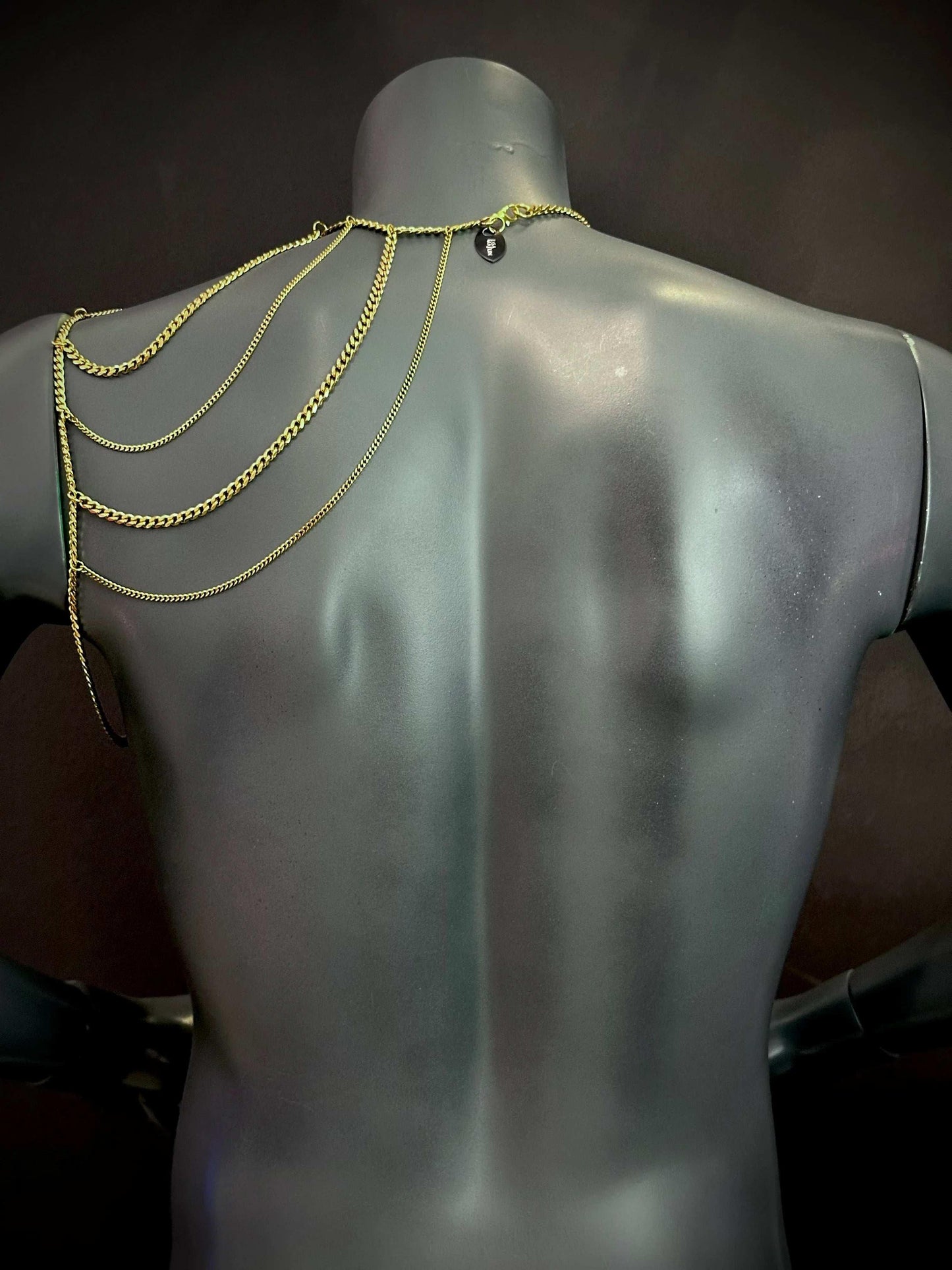 Goldfarbene Wing Bodychain mit mehrreihigen Ketten an schwarzem Schaufenster, elegant und stilvoll