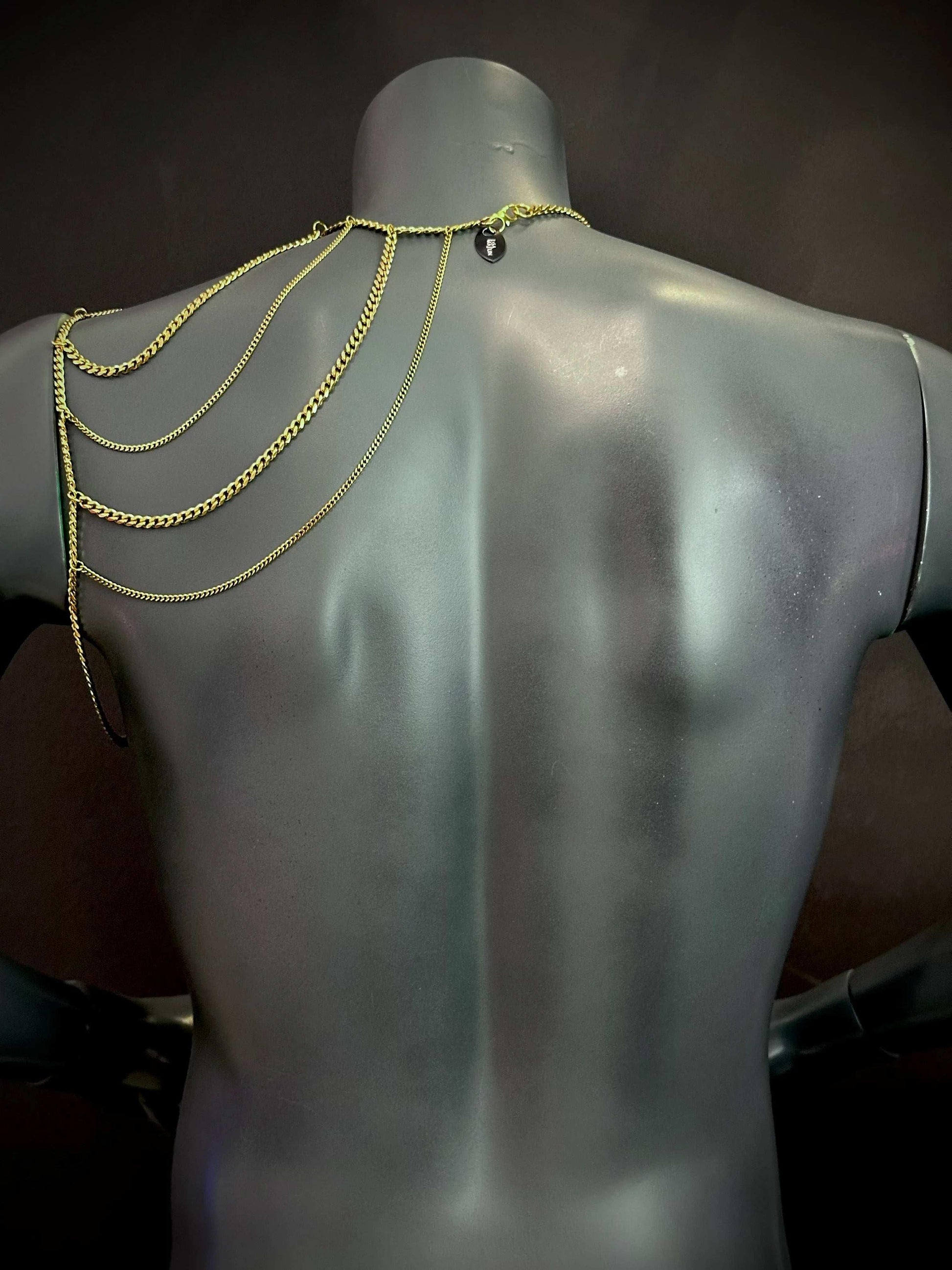 Goldfarbene Wing Bodychain mit mehrreihigen Ketten an schwarzem Schaufenster, elegant und stilvoll