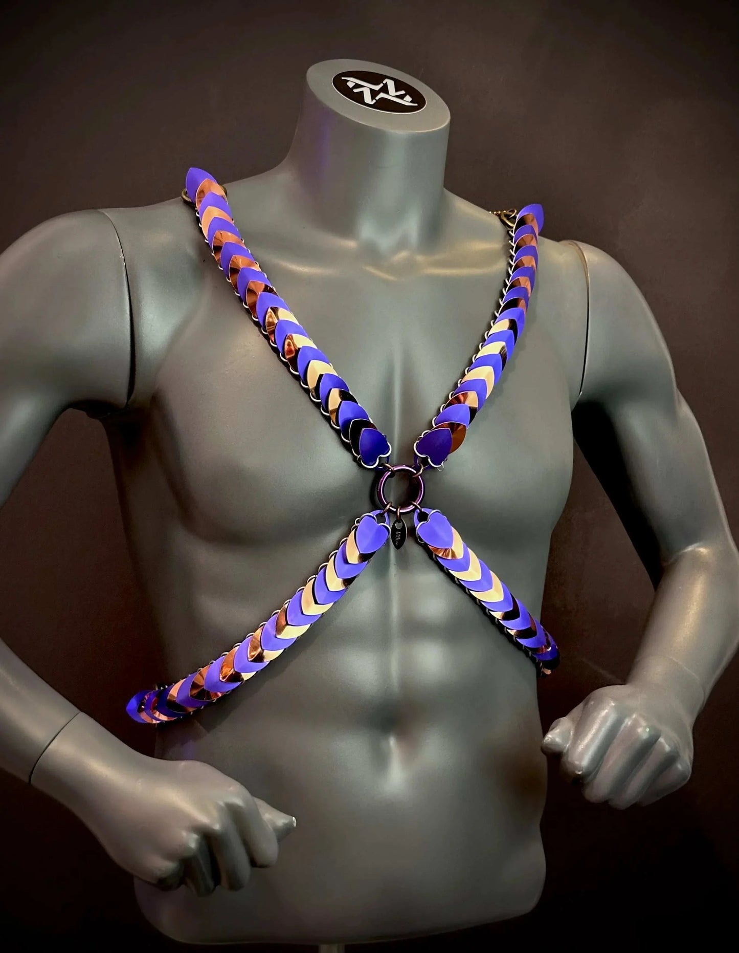 Xenia Harness in Lila und Bronze, moderner Kettenstil, ausdrucksstark und kraftvoll am grauen männlichen Torso