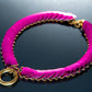 Pink Choker aus geflochtenem Material mit goldfarbenem Ring, modern und elegant wirkend